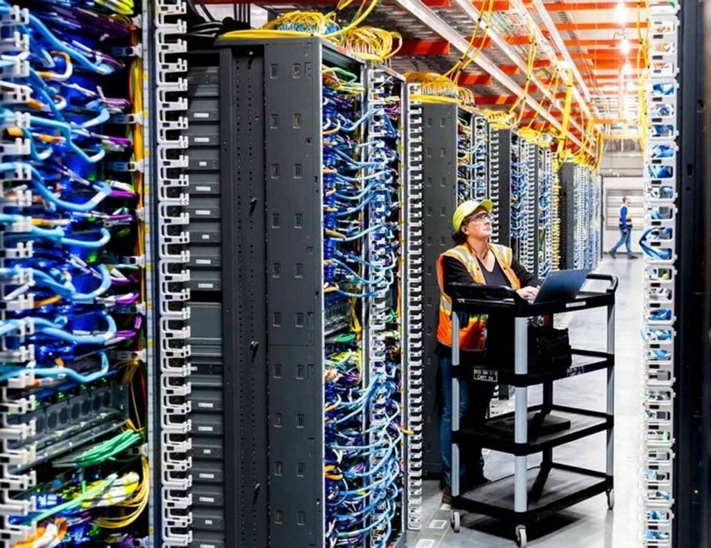 A network technician working on server racks in a high-density data center with complex structured cabling.