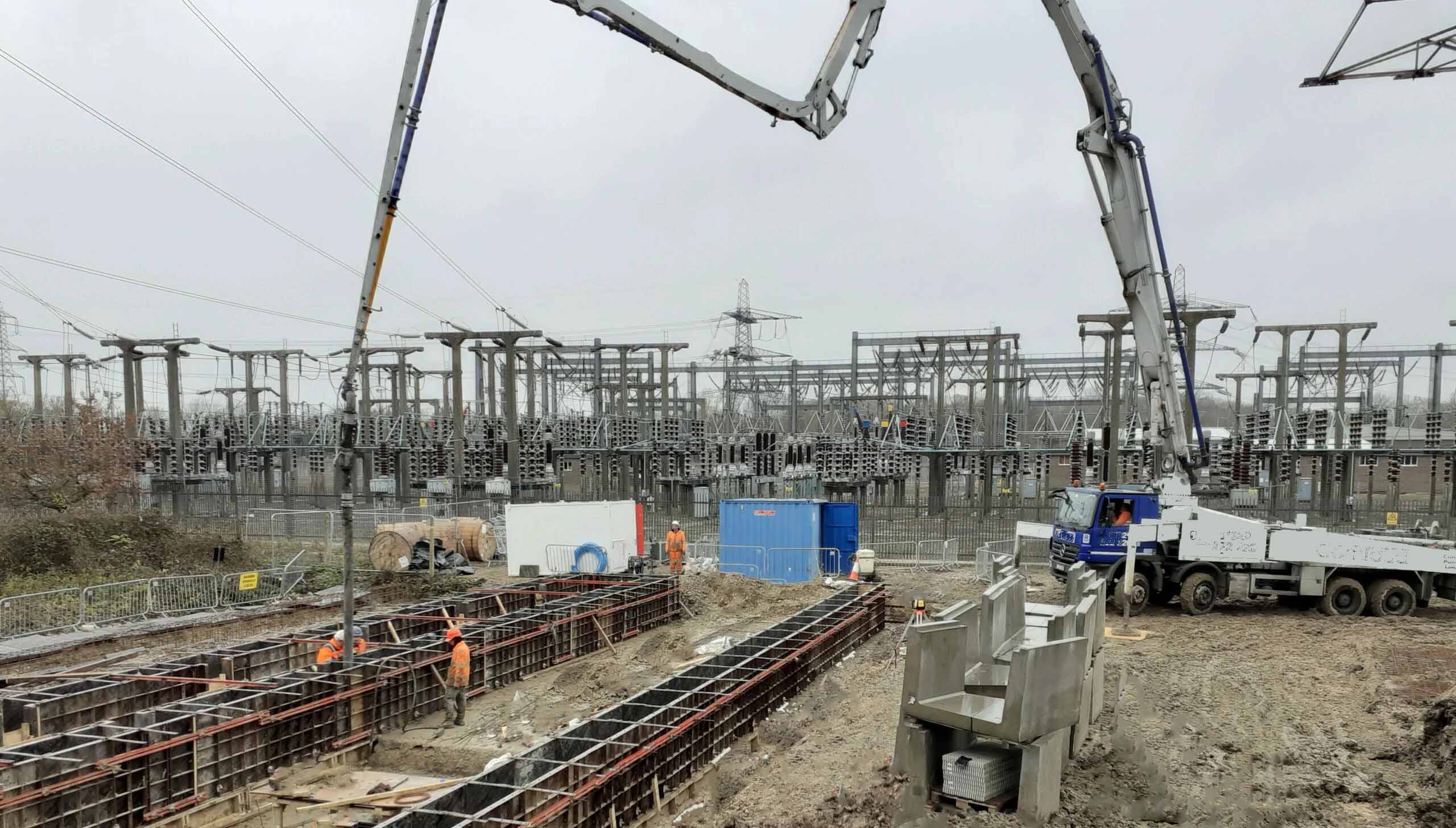 Construction site at an electrical substation featuring concrete foundation formwork and heavy machinery in progress.